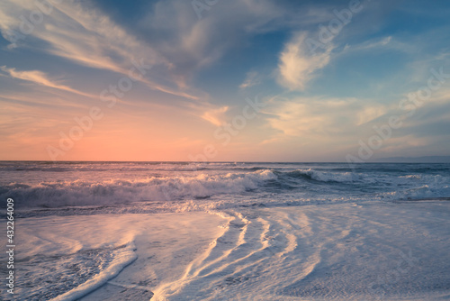 Beach sunset. Empty sand beach  sea waves  and sun setting down the horizon. blue and pink colors  copy space