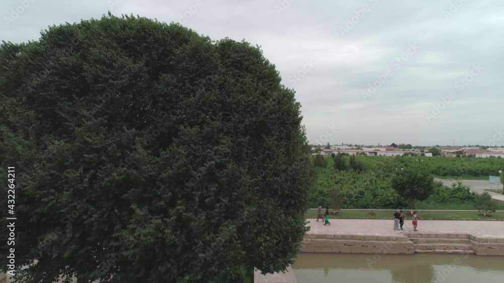 Drone camera flies over the pool in front of the mausoleum of memorial complex of Bahouddin Naqshband near Bukhara. Filmed on a cloudy day. Drone camera flies over the pool in front of the mausoleum of memorial complex of Bahouddin Naqshband near Bukhara. Filmed on a cloudy day.