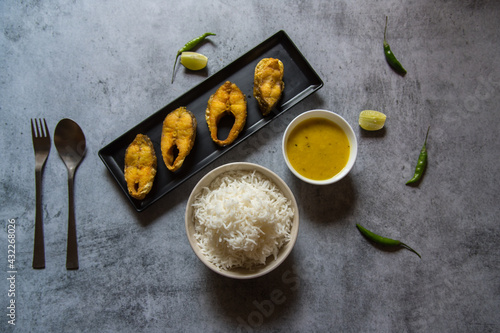 Bengali style lunch menu fried fish served with steamed rice and pulses. View from top, selective focus. 