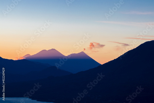 view of the volcanoes and one of them making a small eruption surrounded by mountains in the early hours of the morning with a beautiful sky with warm tones