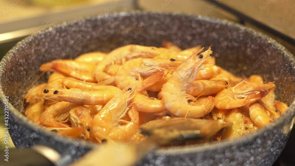 Putting raw shrimp with your hands in a hot frying pan Putting raw shrimp with your hands in a hot frying pan