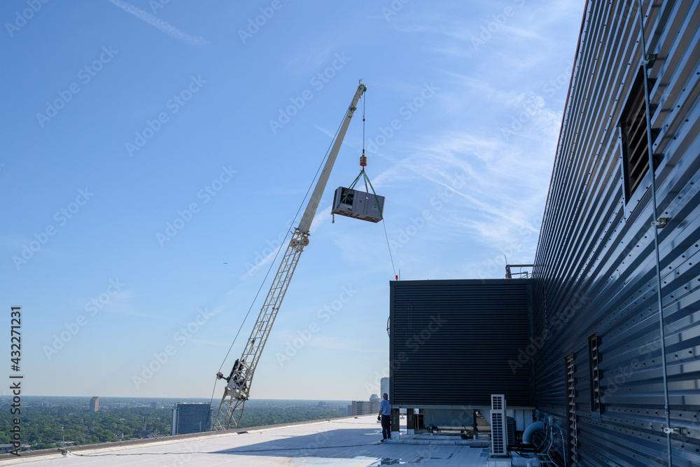 Large commercial chiller air conditioner being lifted onto roof of high ...