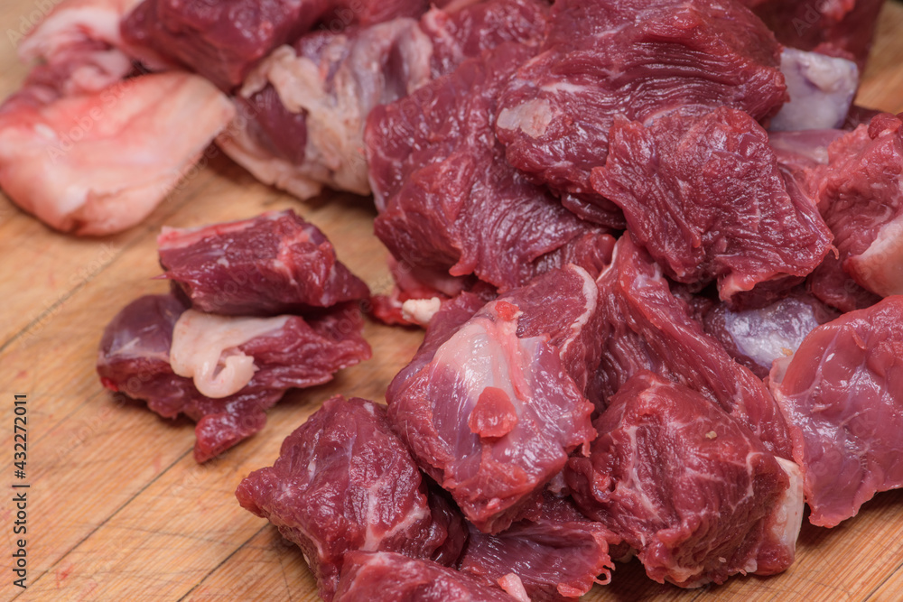 Cuttings of raw beef cut with a knife are placed on a chopping board, ready to cook. Cuttings of raw beef cut with a knife are placed on a chopping board, ready to cook.