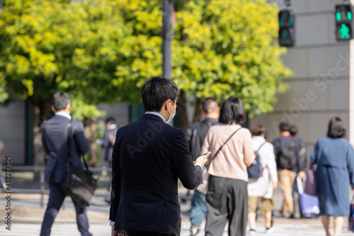 緑を背景にした通勤するビジネマンたちの後ろ姿