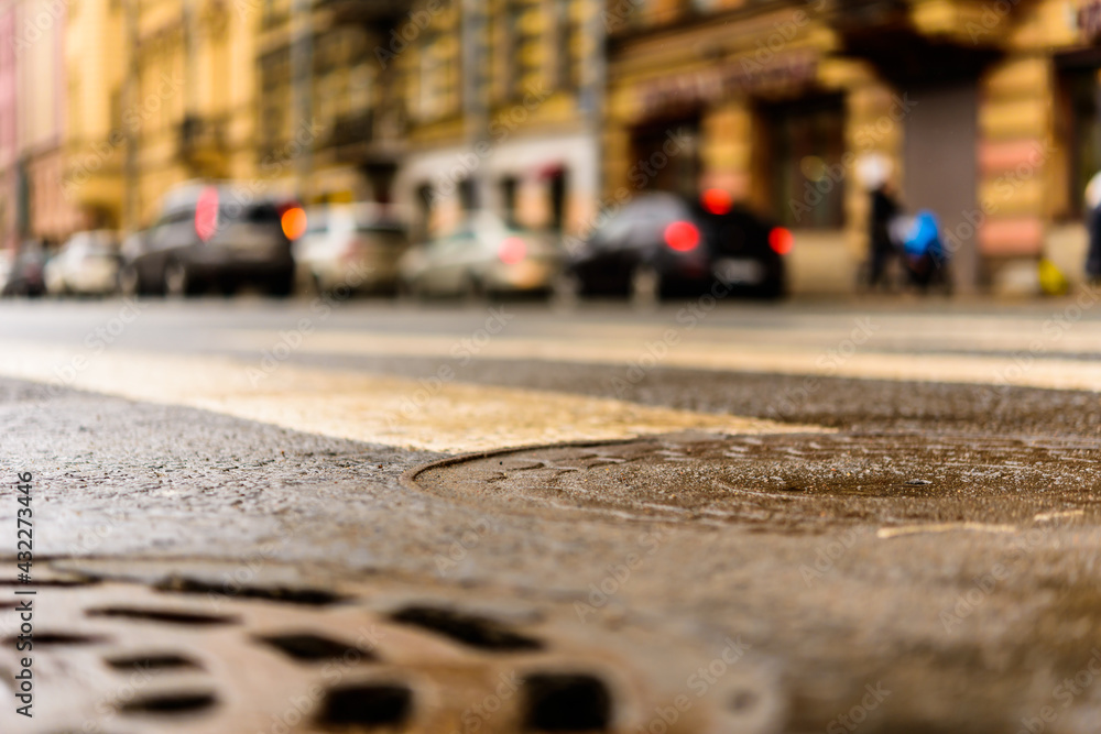 Rainy day in the big city, the pedestrian crossing. Close up view of a hatches at the level of the asphalt