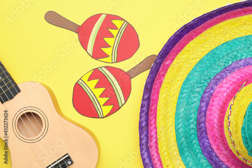 Mexican sombrero  guitar and drawn maracas on color background