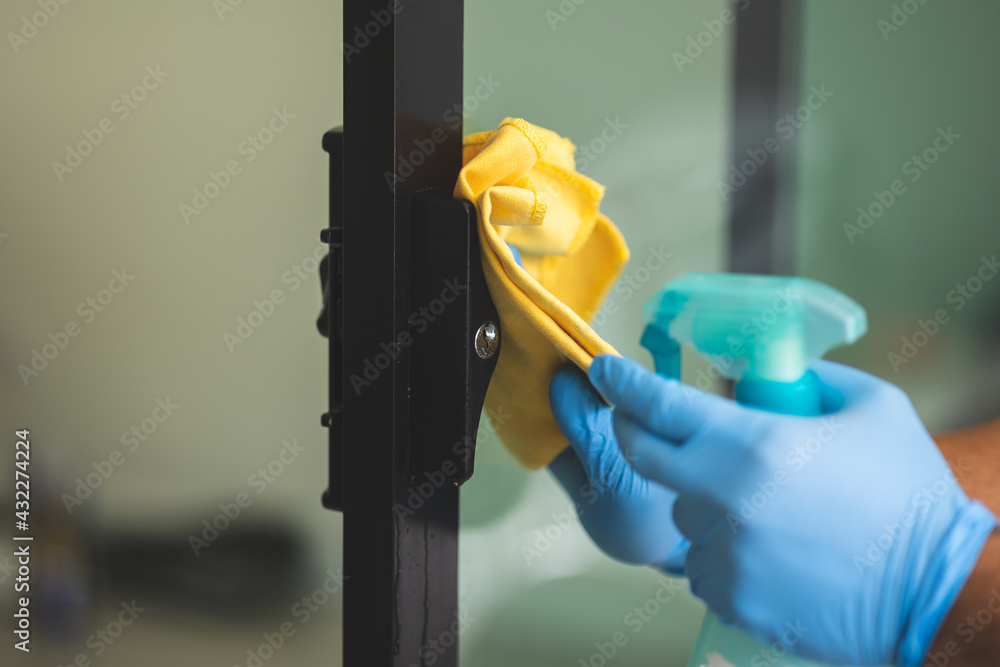 A young man cleans the handrail by spraying a cleaning agent to kill viruses for good hygiene. He put on rubber gloves and wipes. A young man cleans the handrail by spraying a cleaning agent to kill viruses for good hygiene. He put on rubber gloves and wipes.
