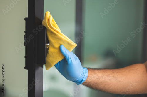 Wallpaper Mural A young man cleans the handrail by spraying a cleaning agent to kill viruses for good hygiene. He put on rubber gloves and wipes. Torontodigital.ca