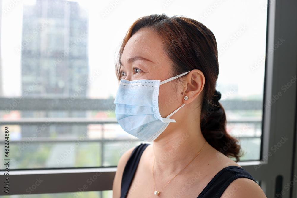 beautiful attractive middle age southeast asian woman wearing blue antiviral surgical mask urban daylight window background beautiful attractive middle age southeast asian woman wearing blue antiviral surgical mask urban daylight window background