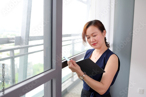 beautiful attractive middle age southeast asian woman home office work read see document book note standing near glass window look at camera urban daylight window background Free Download beautiful attractive middle age southeast asian woman home office work read see document book note standing near glass window look at camera urban daylight window background - GFXLoad
