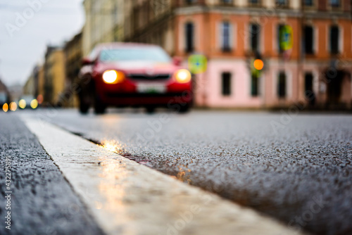 Rainy day in the big city  the red car rides ahead on the road. Close up view from the level of the dividing line