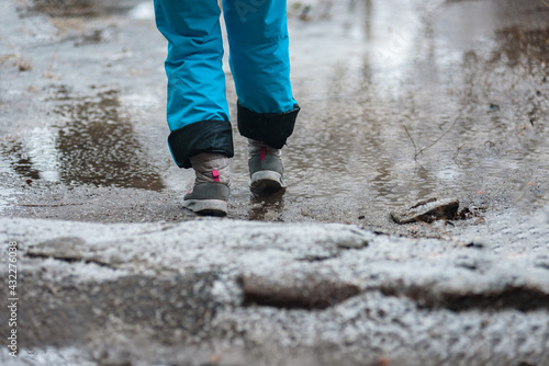Person in warm shoes standing on wet winter road photo