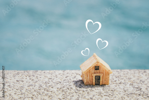 miniature house and  heart shape on concrete floor with blurred blue background, copy space, home sweet home , valentine, happy family concept