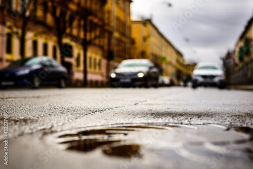 Rainy day in the big city, the headlights of the approaching car. Close up view of a hatch at the level of the asphalt © Georgii Shipin
