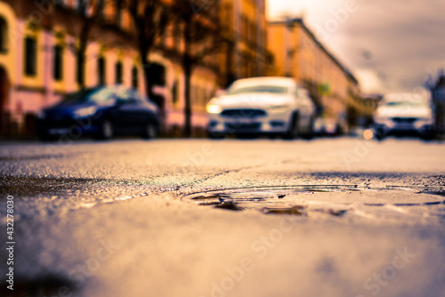 Rainy day in the big city, the approaching car. Close up view of a hatch at the level of the asphalt © Georgii Shipin