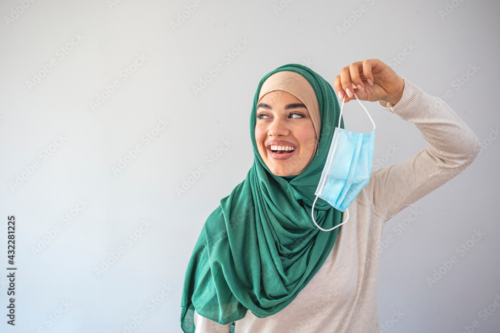 Muslim Woman taking off mask. Removing mask from face. We are safe. Coronavirus ended. Quarantine is over concept. The young beautiful Muslim woman takes off the medical mask Muslim Woman taking off mask. Removing mask from face. We are safe. Coronavirus ended. Quarantine is over concept. The young beautiful Muslim woman takes off the medical mask