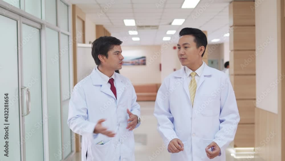 Wide shot of Hospital or healthcare lobby waiting area with group of professional doctor walking through corridor hallway and talk about patient symptoms. Hospital and medical health center concept. Wide shot of Hospital or healthcare lobby waiting area with group of professional doctor walking through corridor hallway and talk about patient symptoms. Hospital and medical health center concept.