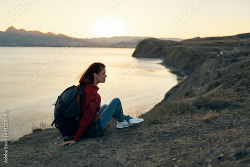 a traveler with a backpack looks at the sunset at the sea in the mountains © SHOTPRIME STUDIO