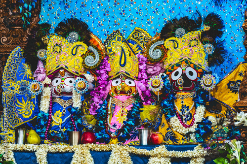 Indian Lord jagannath balaram subhadra three statues with colourful clothing and jewellery decorated with bright and vibrant flowers at a temple.