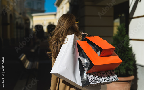 Successful shopping! A young attractive European woman holding in her hands a lot of shopping packages from various clothing and footwear stores
