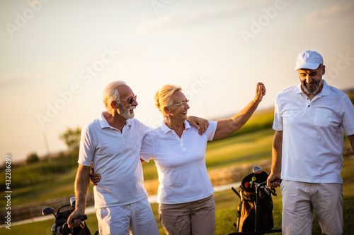 Three senior golfers walking and talking.