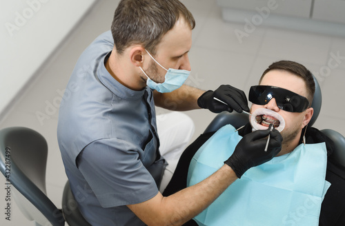 Installing or adjusting braces to correct bite. Male dentist examines the braces. Top view