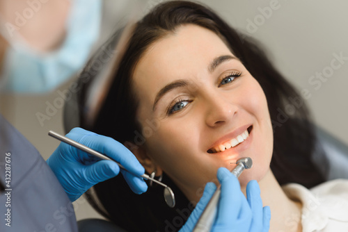 Female dentist examines the smile of a young woman after treatment, teeth brushing or enamel whitening. First person close-up shooting