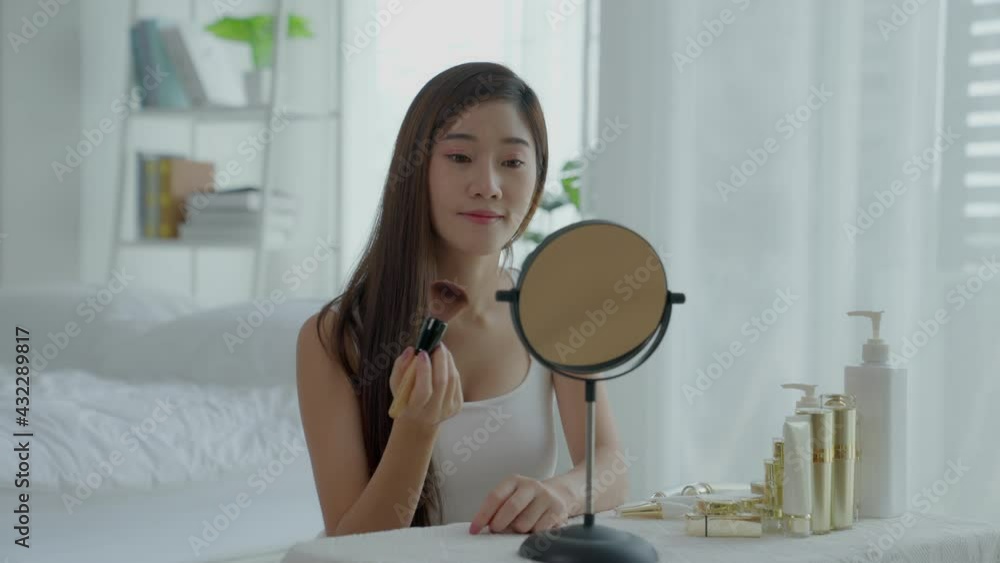 A beautiful Asian woman sitting in the mirror with her makeup in a good mood in the morning.Her pet a dog pug come into troubler the makeup table. Healthy skin care and cosmetic concept A beautiful Asian woman sitting in the mirror with her makeup in a good mood in the morning.Her pet a dog pug come into troubler the makeup table. Healthy skin care and cosmetic concept