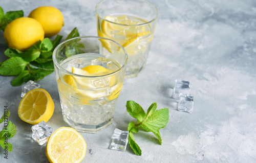 Cold lemonade with lemon, mint and ice on a concrete background.