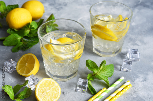 Cold lemonade with lemon, mint and ice on a concrete background.