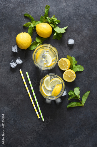 Cold lemonade with mint and ice on a black concrete background, top view.