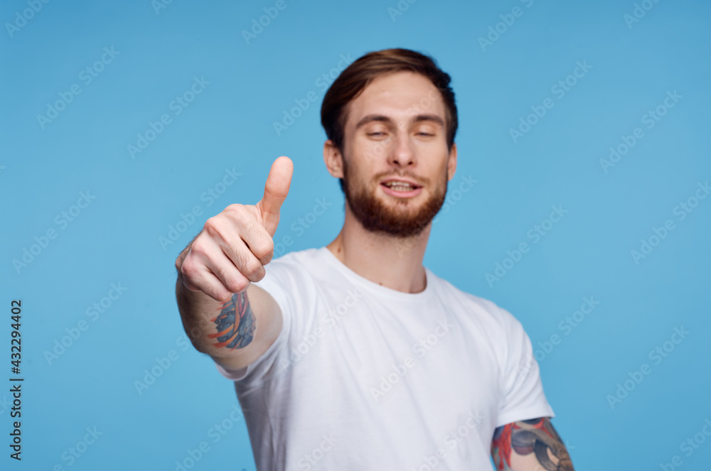 man in white t-shirt showing thumb up blue background studio