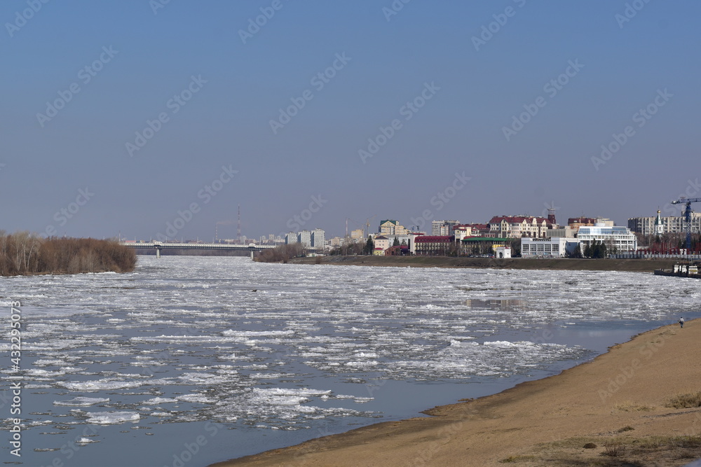 Spring city landscape. Early spring, ice drift on the river. View from the shore of the ice drift and the city.