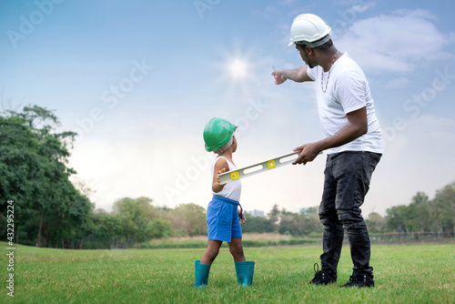 African father pointed a finger at bright star over green park and explained the to his son, standing on lawn at park, target and success concept