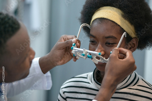 African Optometrist use trial frame checking child girl patient vision at ophthalmology clinic