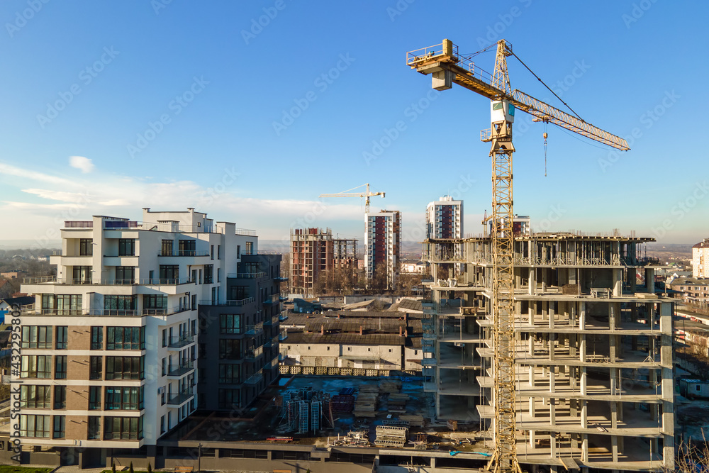 Aerial view of high tower crane and residential apartment buildings under construction. Real estate development. Aerial view of high tower crane and residential apartment buildings under construction. Real estate development.