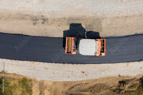 Aerial view of new road construction with steam roller machine at work. photo