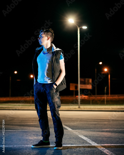 Guy at night in the parking lot against the background of lanterns photo