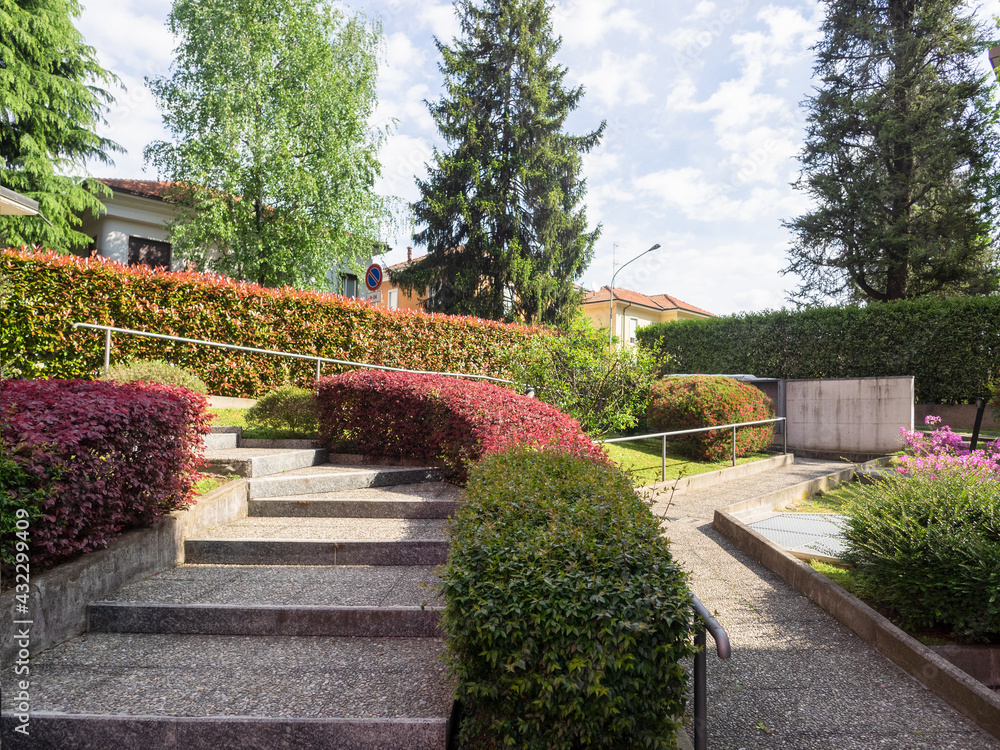 condominium entrance staircase and disabled ramp in a lush garden