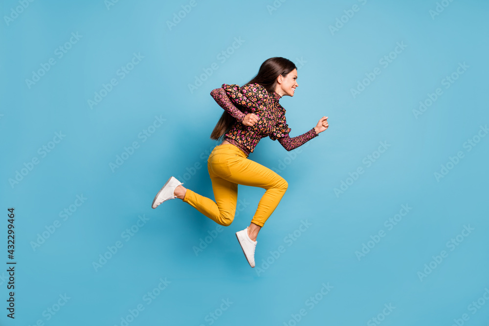 Profile side full size photo of young happy smiling charming woman running fast isolated on blue color background Profile side full size photo of young happy smiling charming woman running fast isolated on blue color background