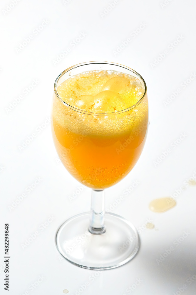 Glass goblet with bubbling orange liquid on a white background.