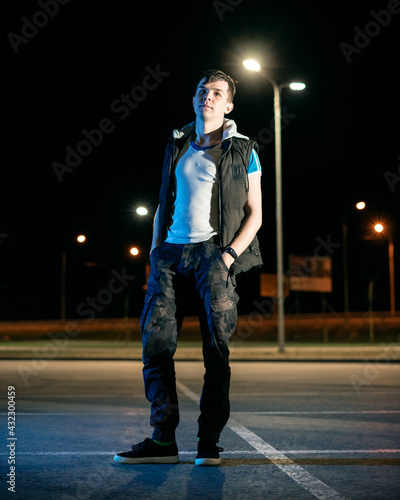 A young boy stands in a park at night, illuminated by a blue light photo