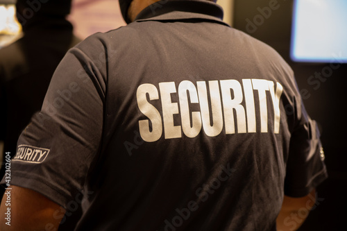 Fototapeta Rear view of security guard in uniform patrolling in commercial mall