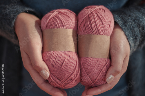 Person hands hold natural color wool alpaca yarn balls with blank labels