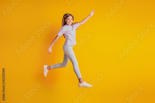 Cheerful sporty girl jumping running isolated over yellow background