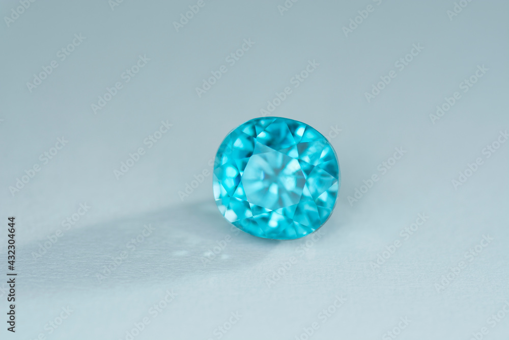 Genuine, natural mined, bright electric neon blue lagoon color, cushion bullet faceted, heated loose zircon flawless gemstone setting for jewelry making. Light gray gradient background. Shade, sparks. Genuine, natural mined, bright electric neon blue lagoon color, cushion bullet faceted, heated loose zircon flawless gemstone setting for jewelry making. Light gray gradient background. Shade, sparks.
