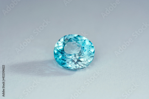 Genuine  natural mined  bright neon blue lagoon color  cushion shaped  heated loose zircon flawless gemstone setting for jewelry making. Light gray gradient background. Shade  shadow.