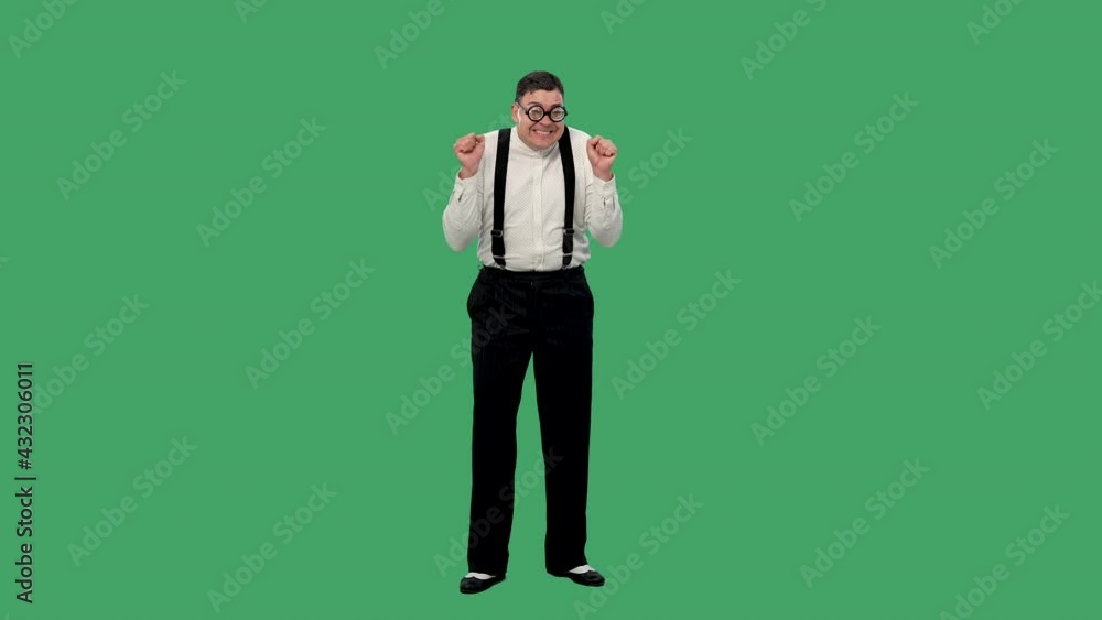 Portrait of a man looking at the camera, rejoicing, celebrating victory, clenching his hands into a fist and smiling. A man in a glasses with thick lenses in the studio on a green screen. Slow motion. Portrait of a man looking at the camera, rejoicing, celebrating victory, clenching his hands into a fist and smiling. A man in a glasses with thick lenses in the studio on a green screen. Slow motion.