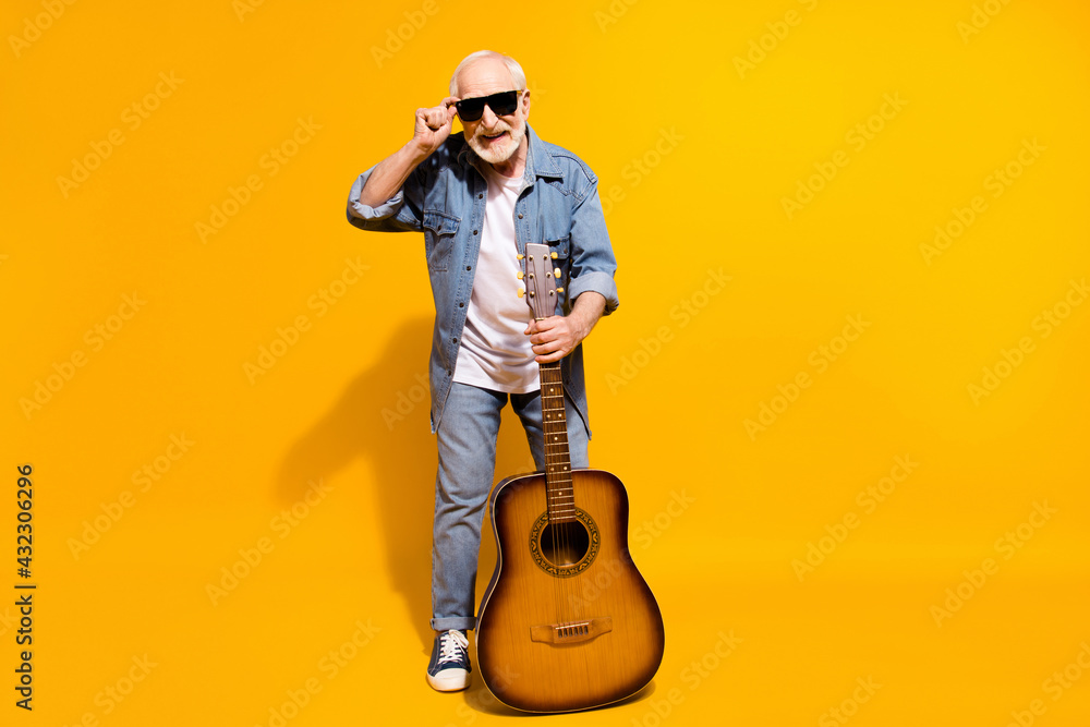 Naklejka premium Full length photo of optimistic cool grey beard old man hold guitar wear spectacles shirt isolated on orange background