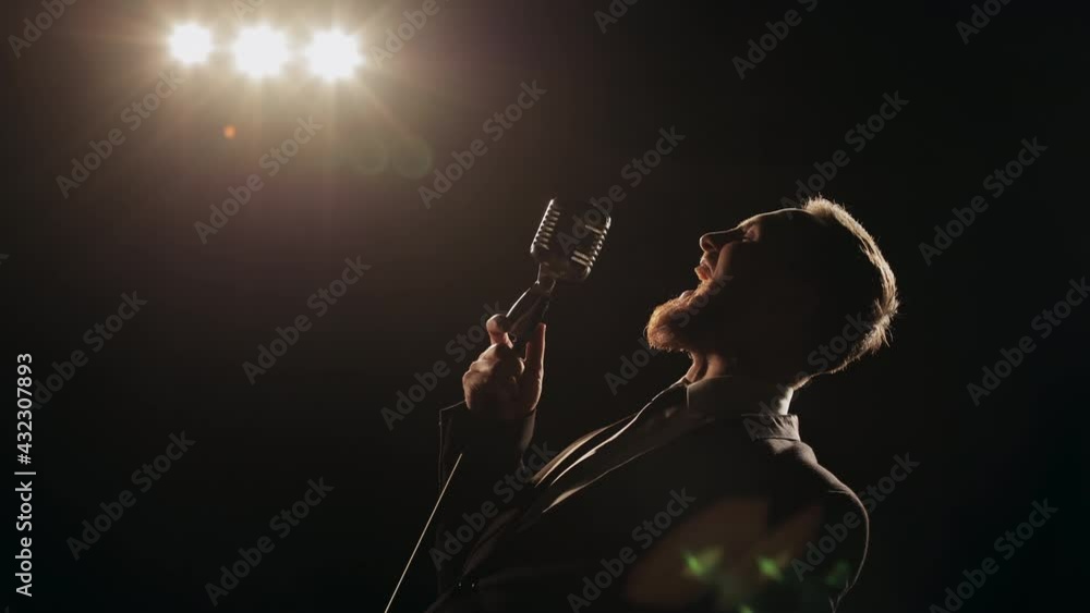 The singer is performing the song emotionally. He's holding a retro ...